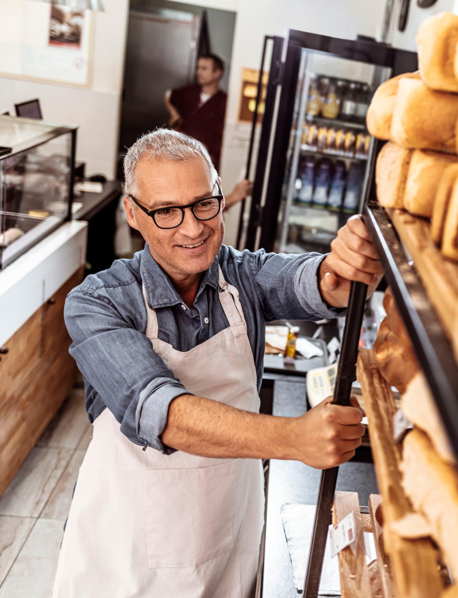 a baker handling a rack full of freshly baked bread