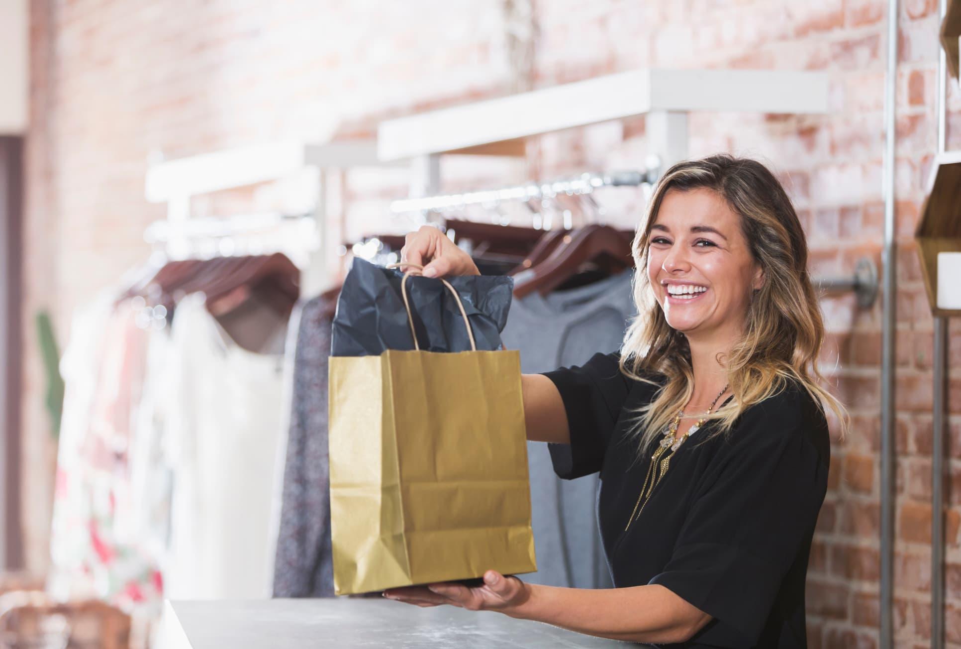 a smiling salesperson hands over a satchel